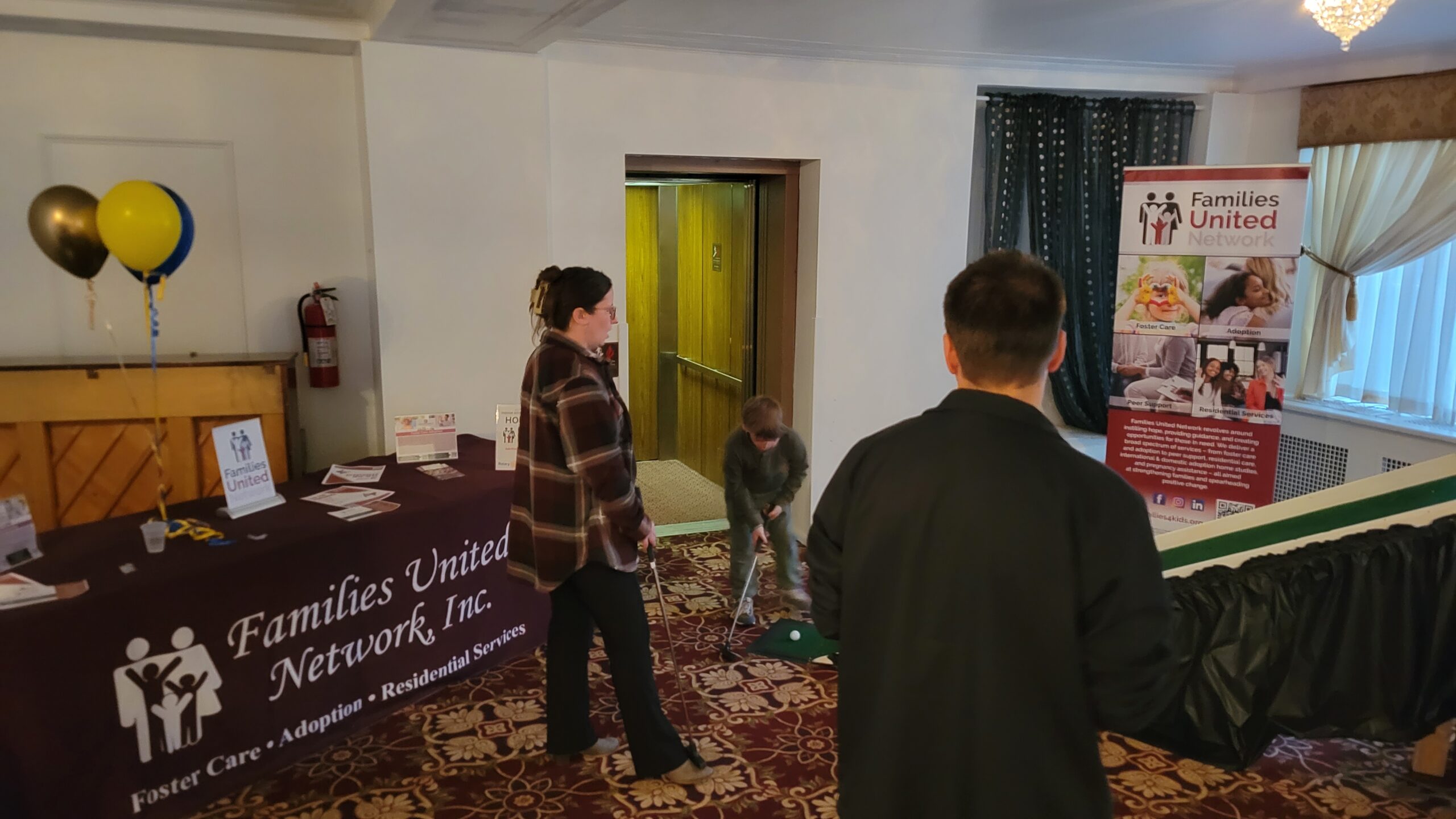 A family watching their little one golf